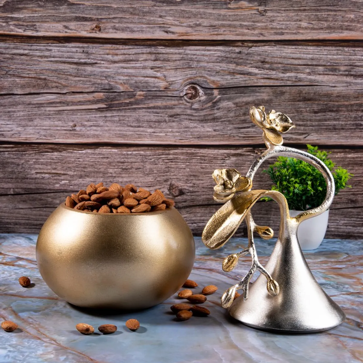 Gold and silver decorative bowl arrangement with almonds and a small plant