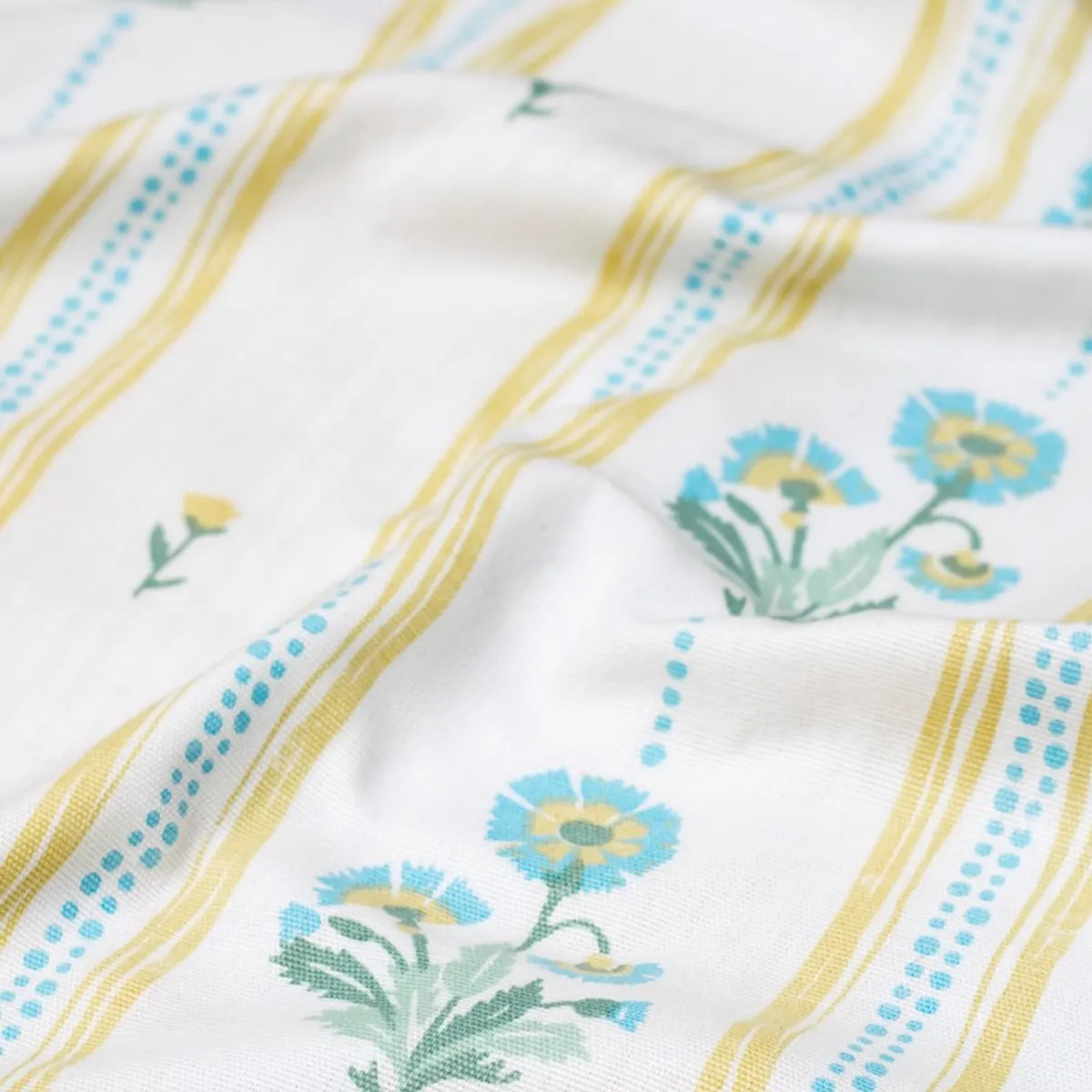 Close-up of soft white curtain fabric with blue and yellow floral stripes