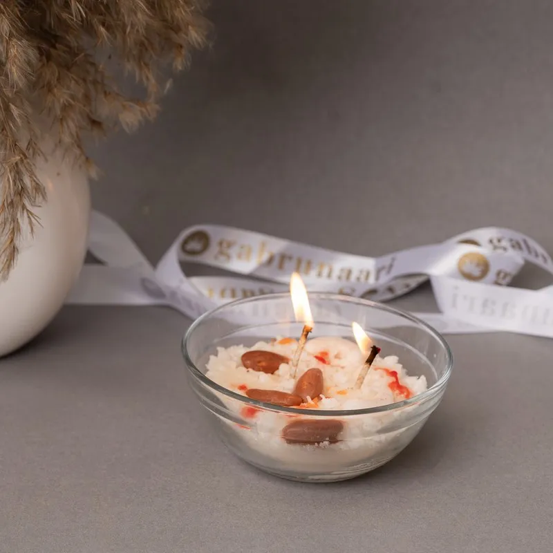 Lit dessert-inspired candle in a clear glass bowl with festive ribbon backdrop
