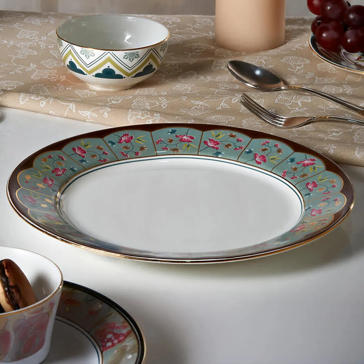 Floral dinner plate with a green and pink decorative rim on a white surface.