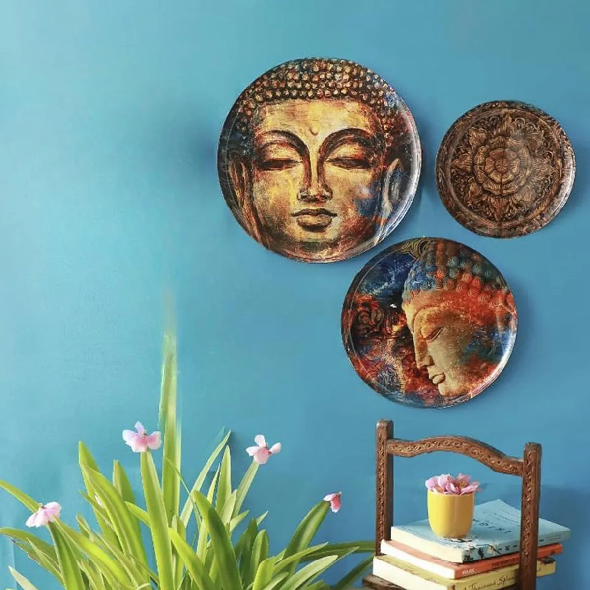 Three Buddha wall plates arranged against a bright blue wall.