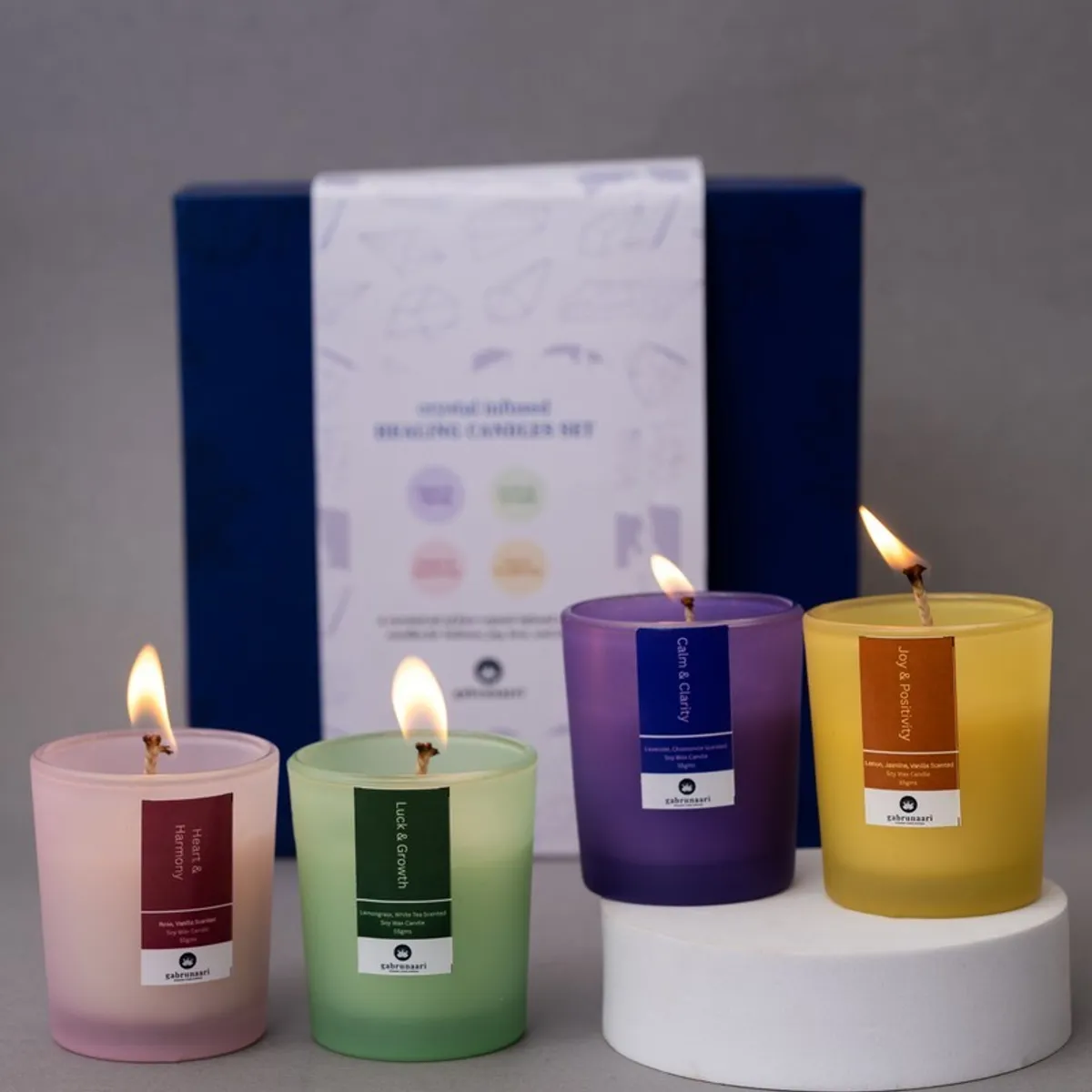 Four coloured candles lit in front of a blue gift box