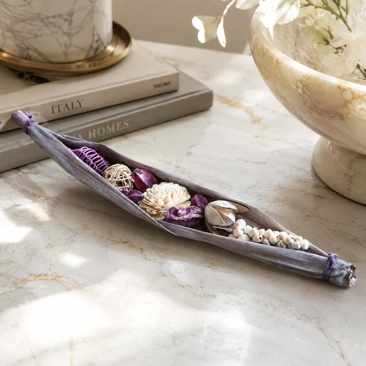 Purple and off-white floral arrangement styled on a marble console with decor.