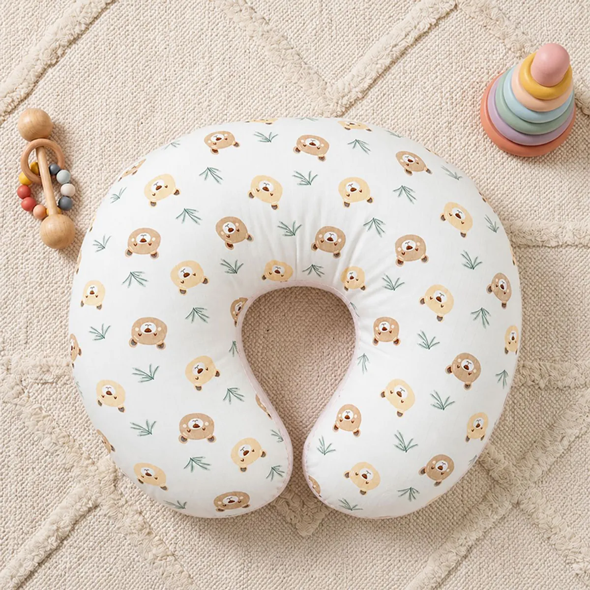 Top view of white U-shape pillow with bear print on a textured rug