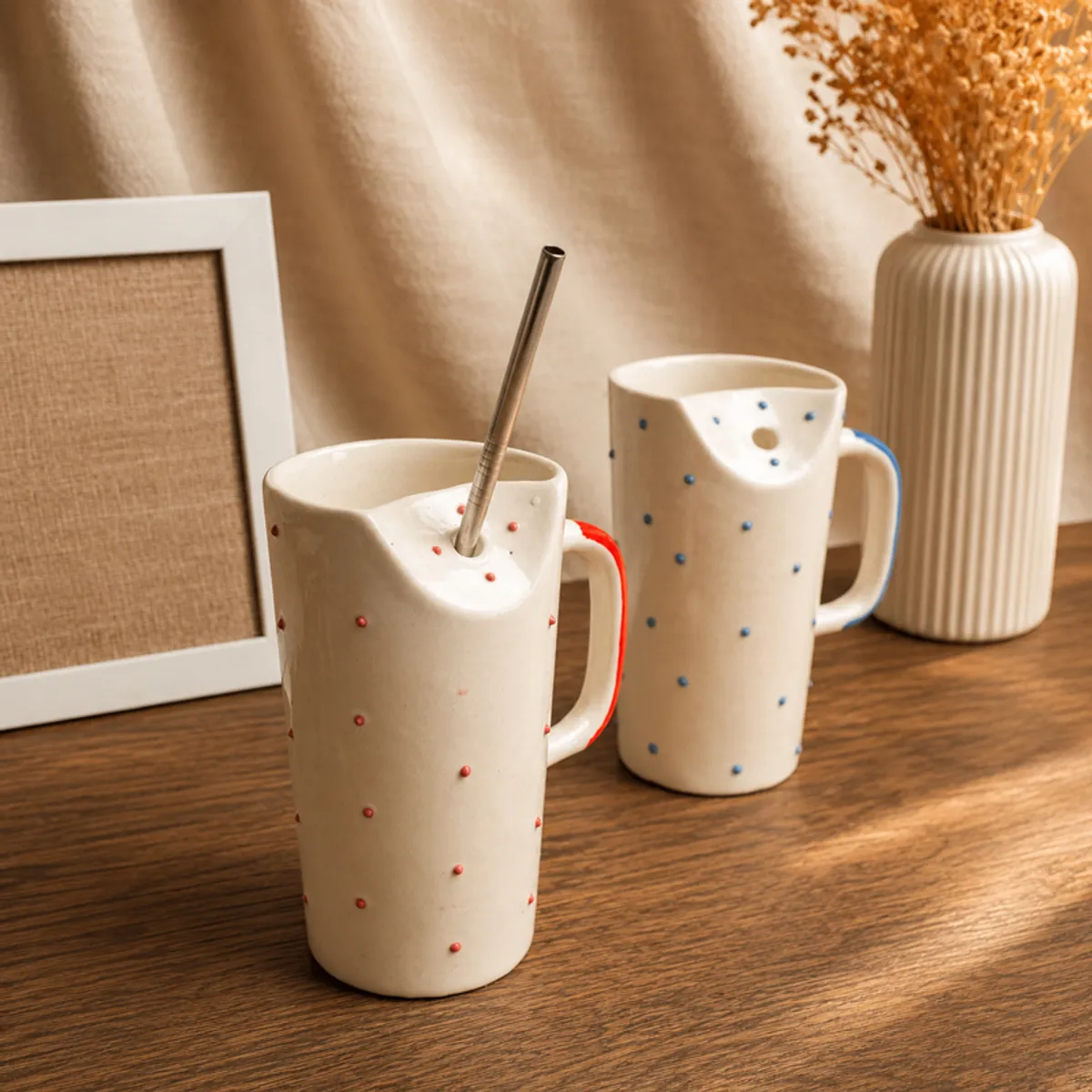 Blue and red dotted ceramic sippers with metal straws displayed on a table