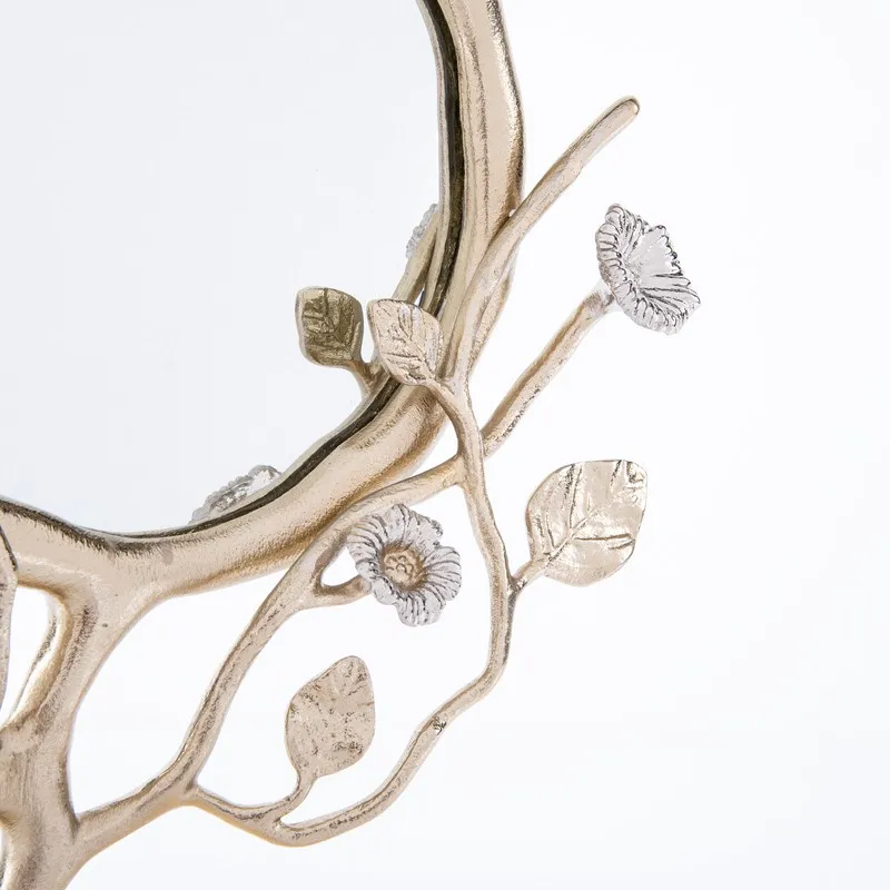 Close-up of the mirror's branching floral frame with leaves and flower details.