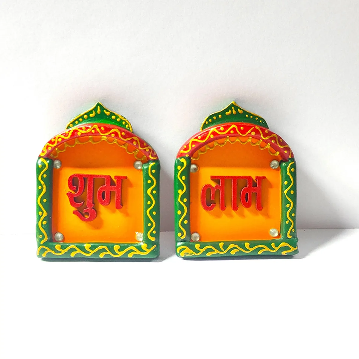 Pair of yellow and green Shubh Laabh wall accents on white surface