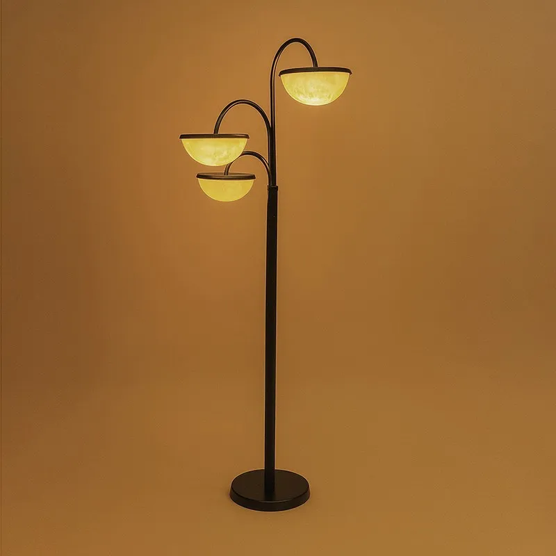 Triple-arm floor lamp illuminated with a warm yellow glow