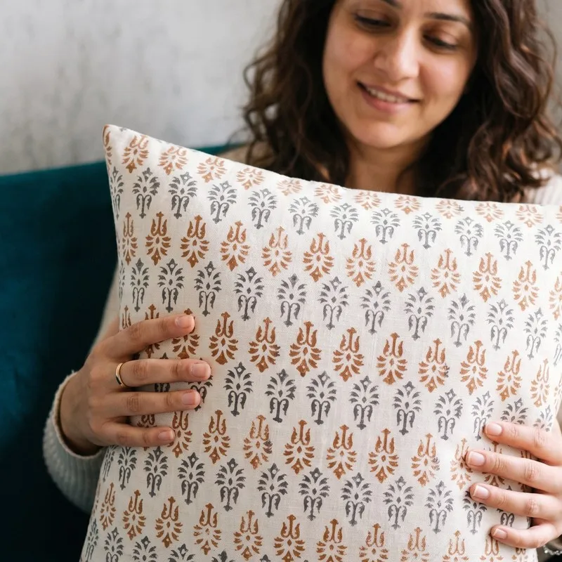 Person holding a white cushion cover with orange and grey printed motifs