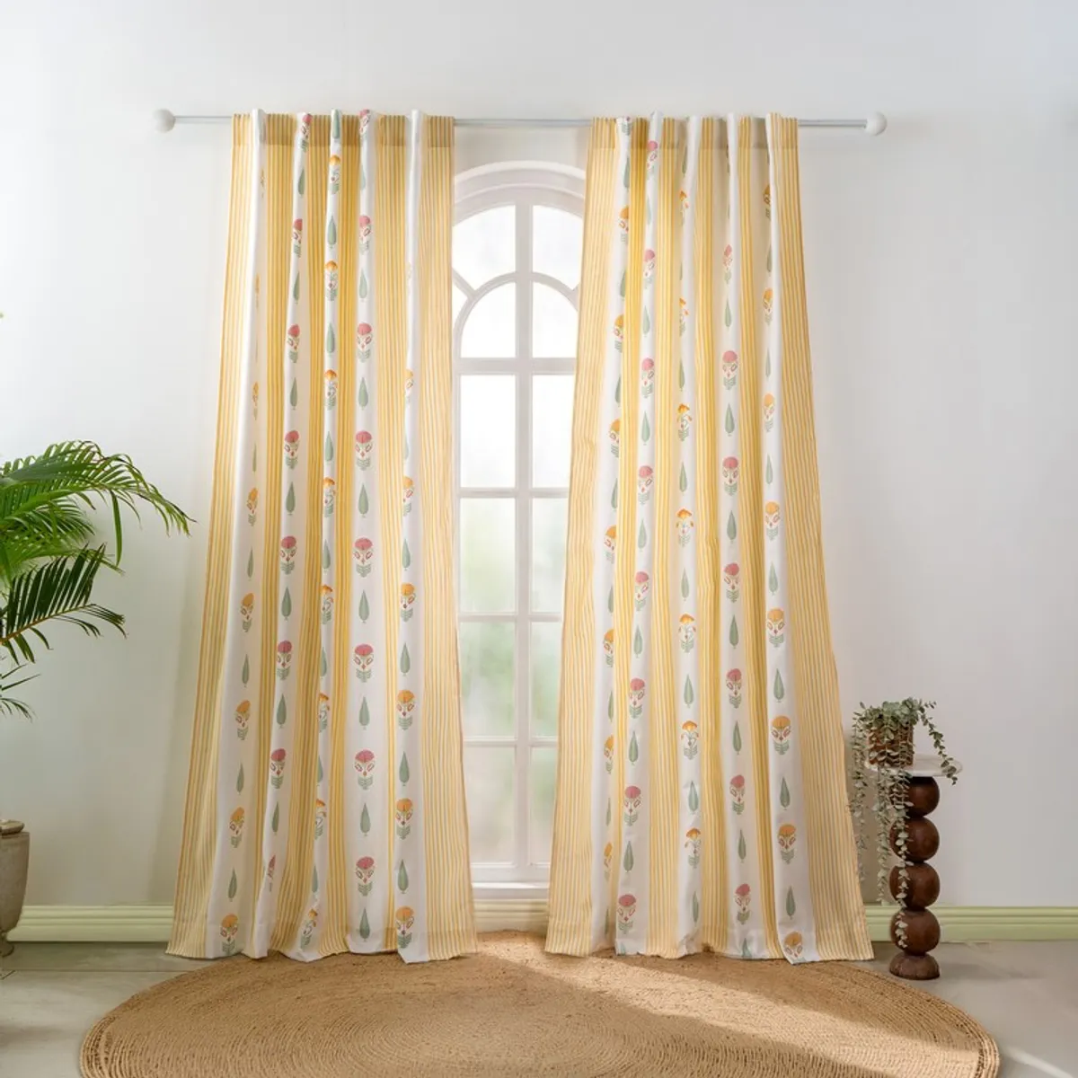 Pair of patterned yellow curtains hanging beside an arched window