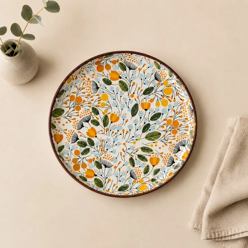 Top view of a round plate with multicolour botanical print and brown rim
