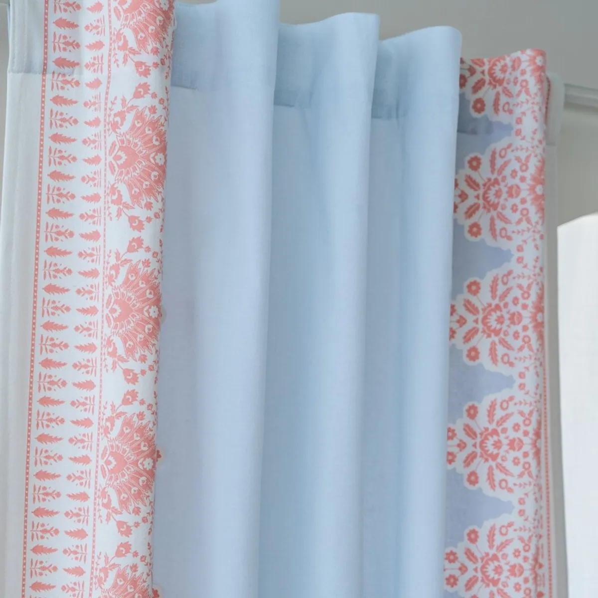 Folded blue curtain showing pink floral border and soft fabric