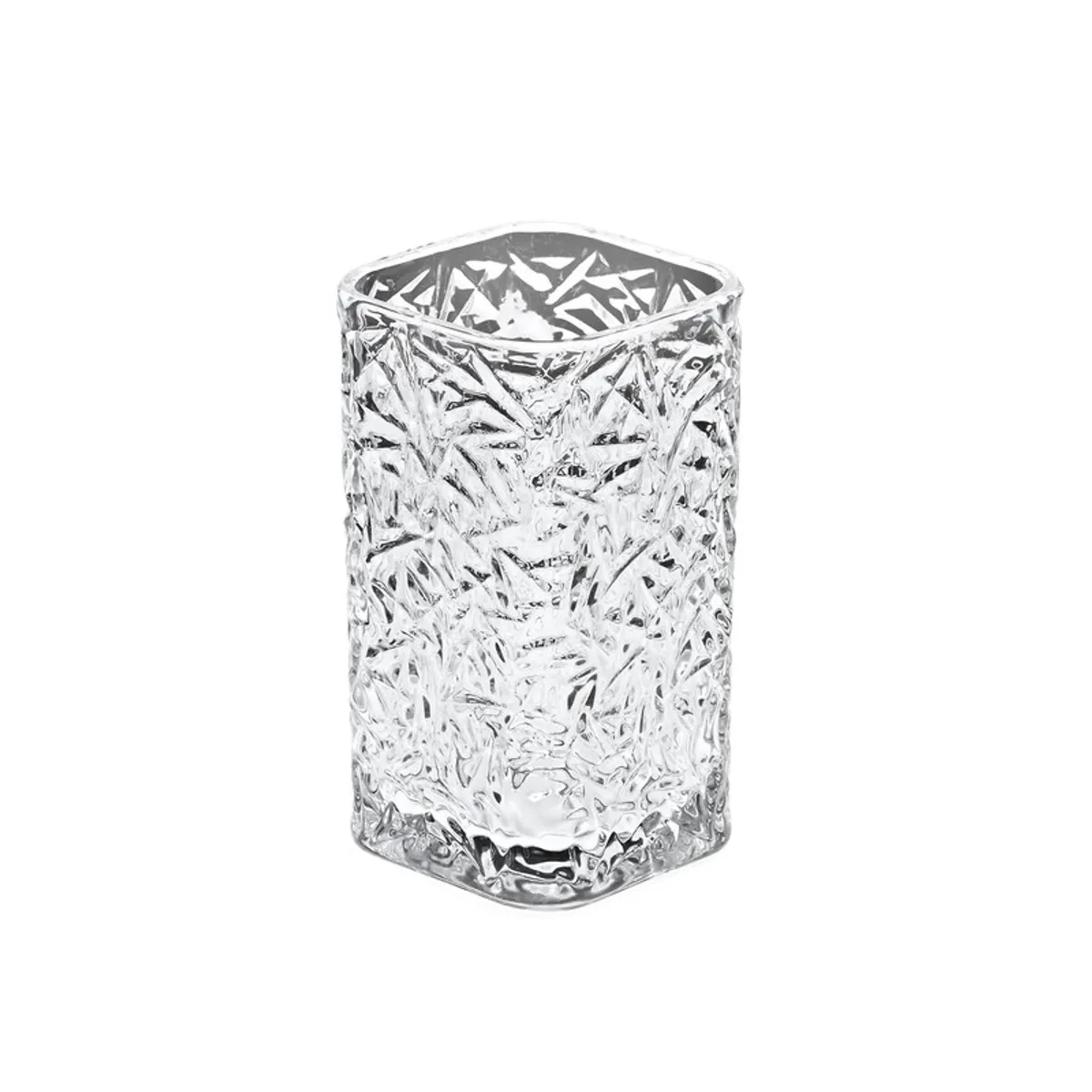 Clear glass tumbler with an abstract cut pattern on a plain background