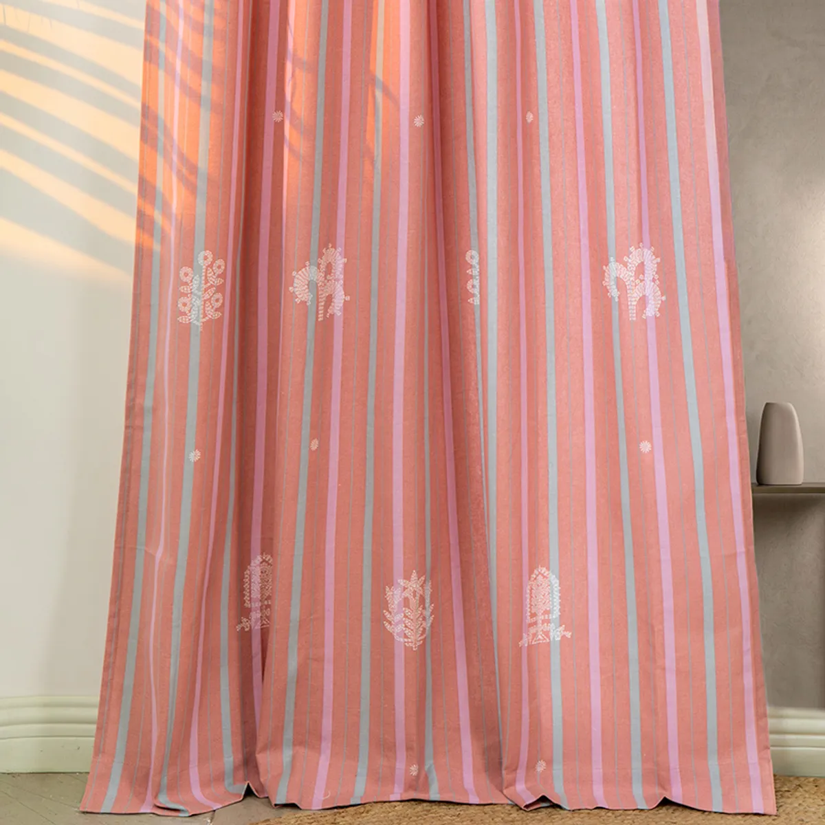Full-length pink striped curtain with pale motifs beside a wall niche