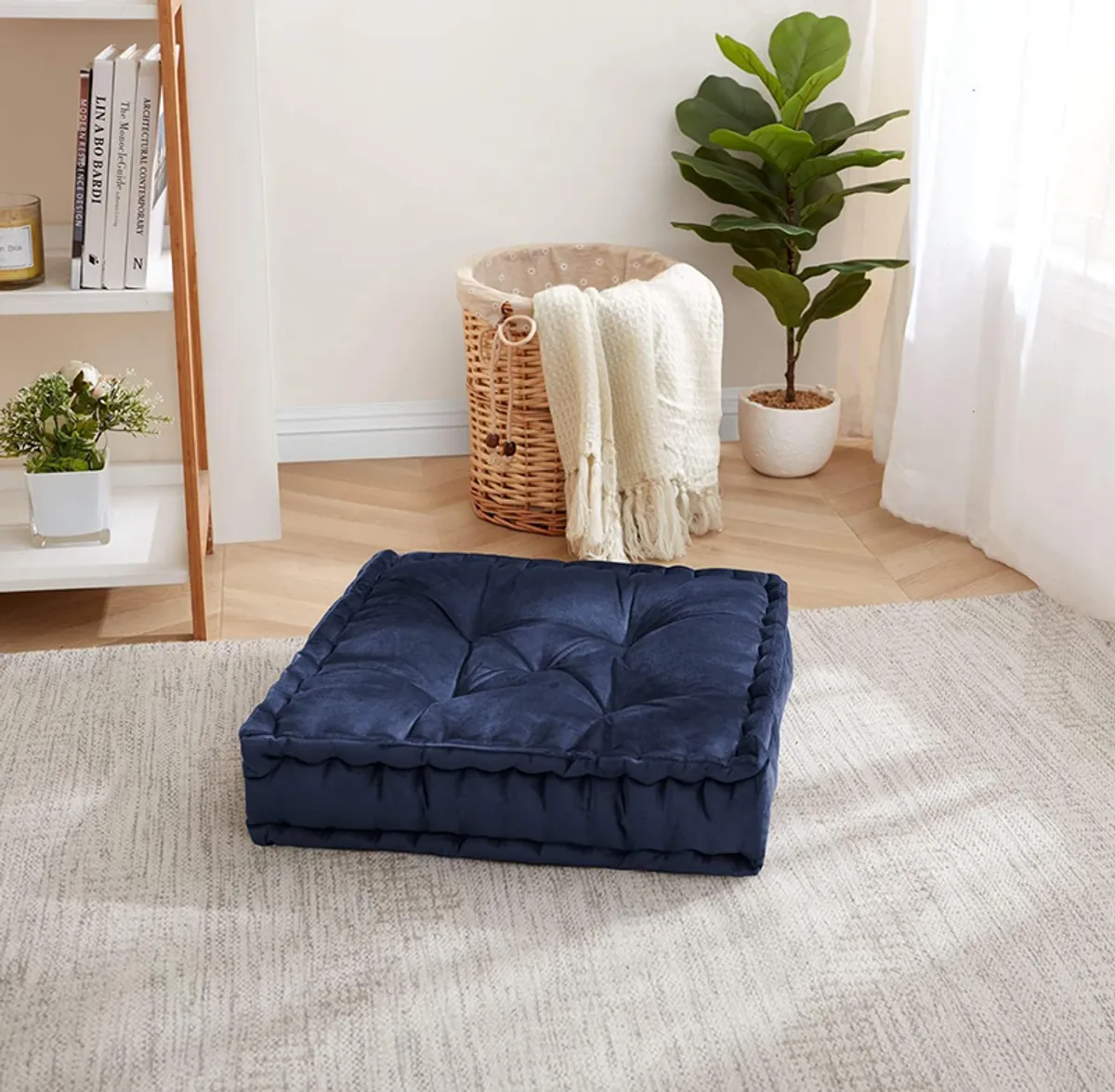 Navy blue square tufted floor cushion styled on a light rug in a room
