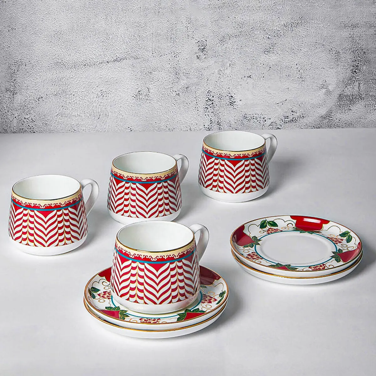 Four white cups with red chevron patterns and matching decorative saucers