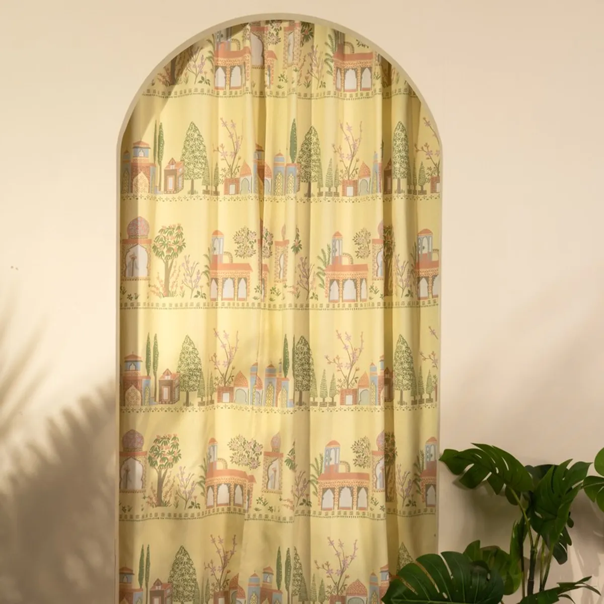 Yellow printed curtain covering an arched doorway with garden motifs