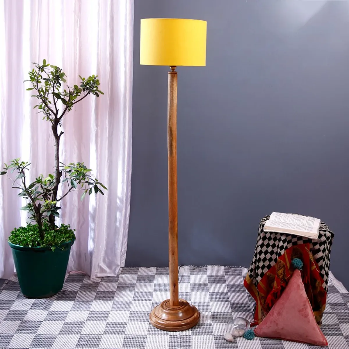 Tall wooden floor lamp with yellow shade in a styled indoor corner