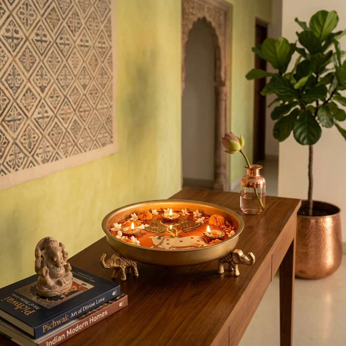 Kamdhenu urli styled on a wooden console with flowers, candles and Indian décor
