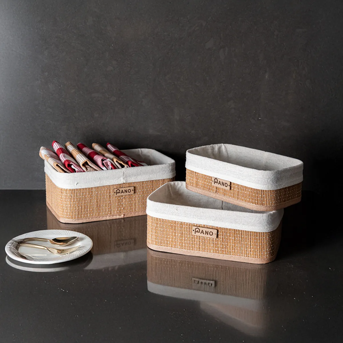 Three rectangular bamboo storage baskets with white fabric lining on a dark surface