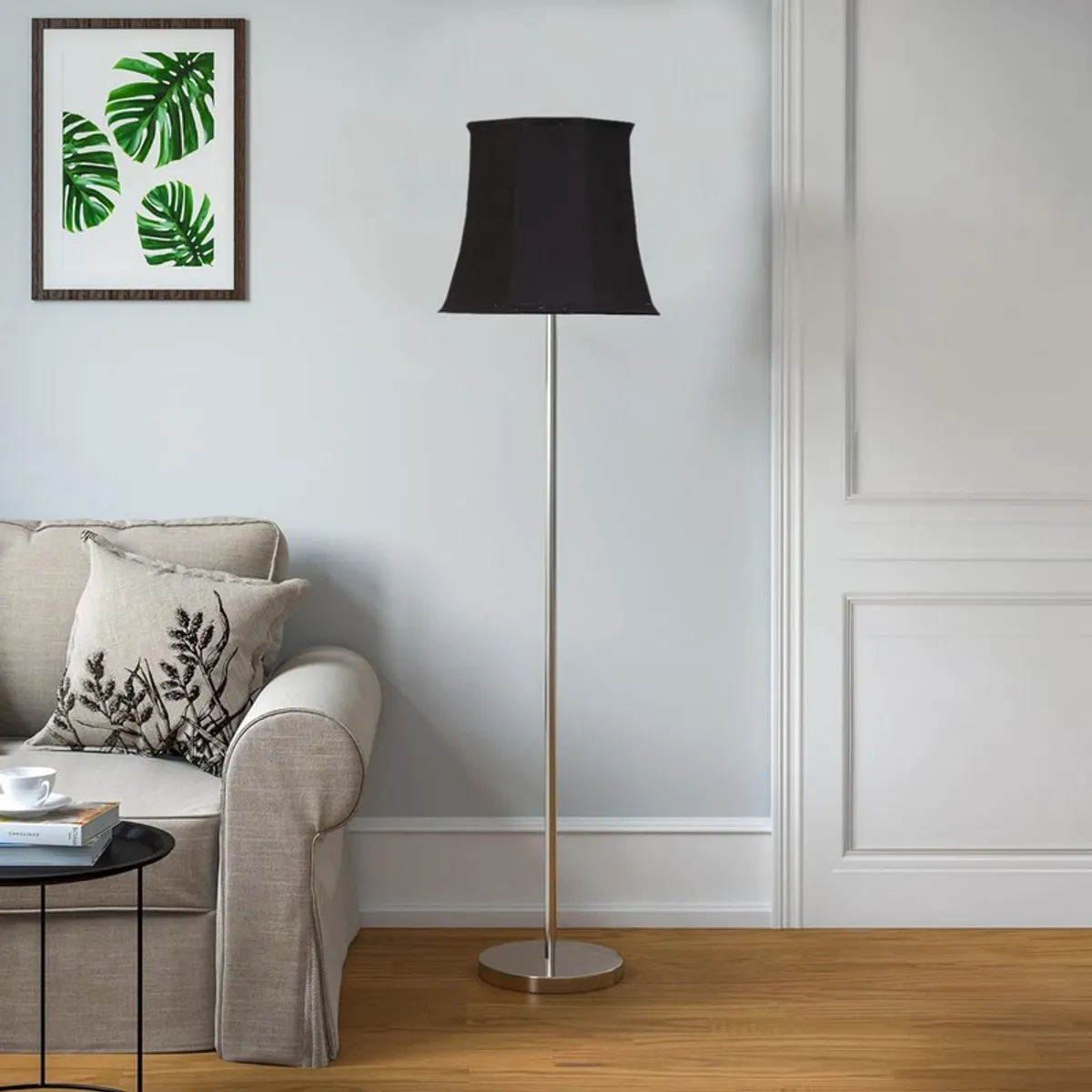 Black floor lamp with slim silver stand against a pale panelled wall