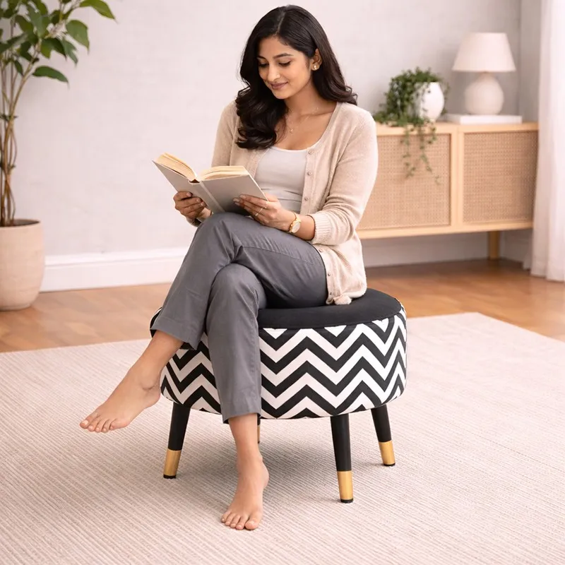 Person seated on a round black-and-white chevron ottoman