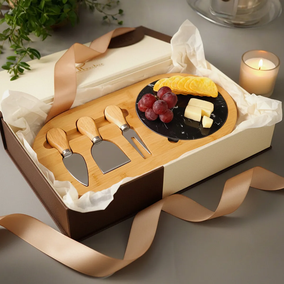 Wooden cheese platter with black marble board and cheese tools arranged in a gift-style setting