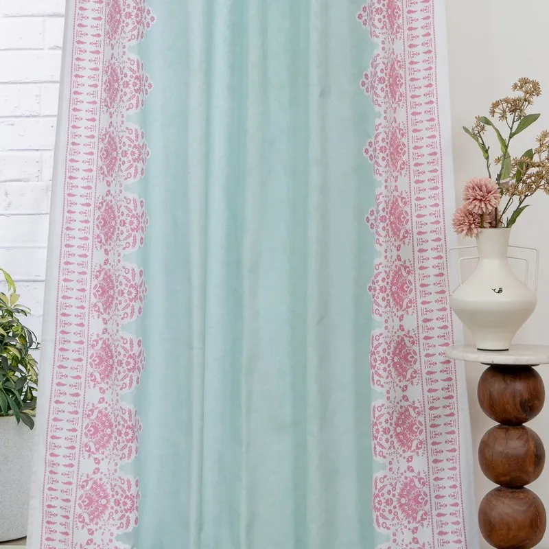 Aqua curtain with symmetrical pink floral borders beside a decorative vase