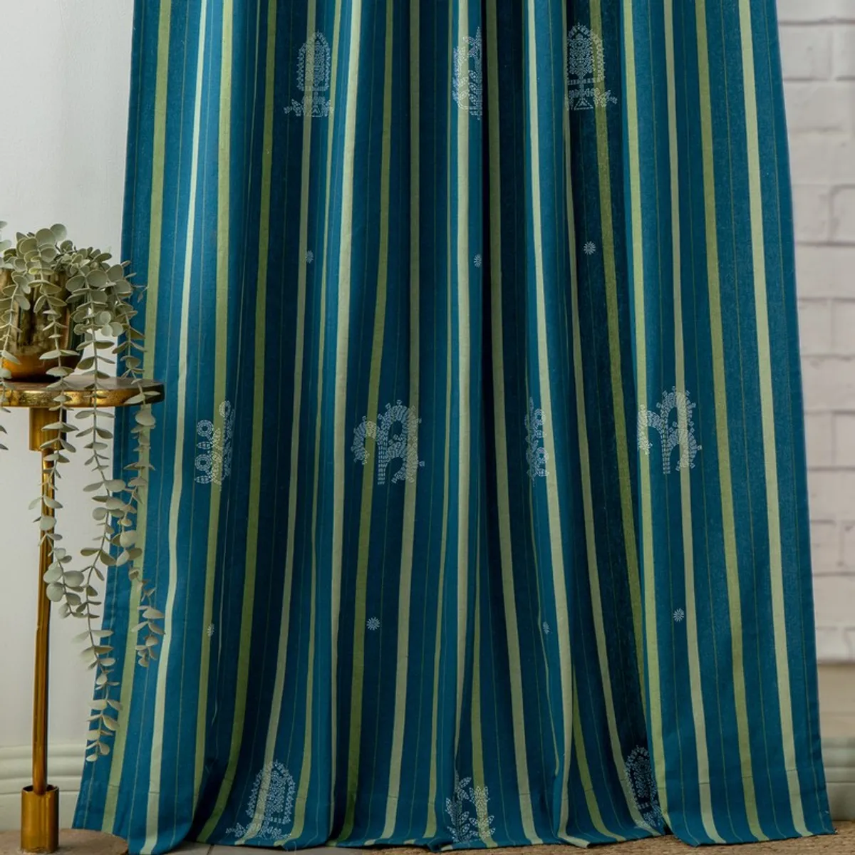 Full-length blue curtains with vertical olive stripes and white motifs