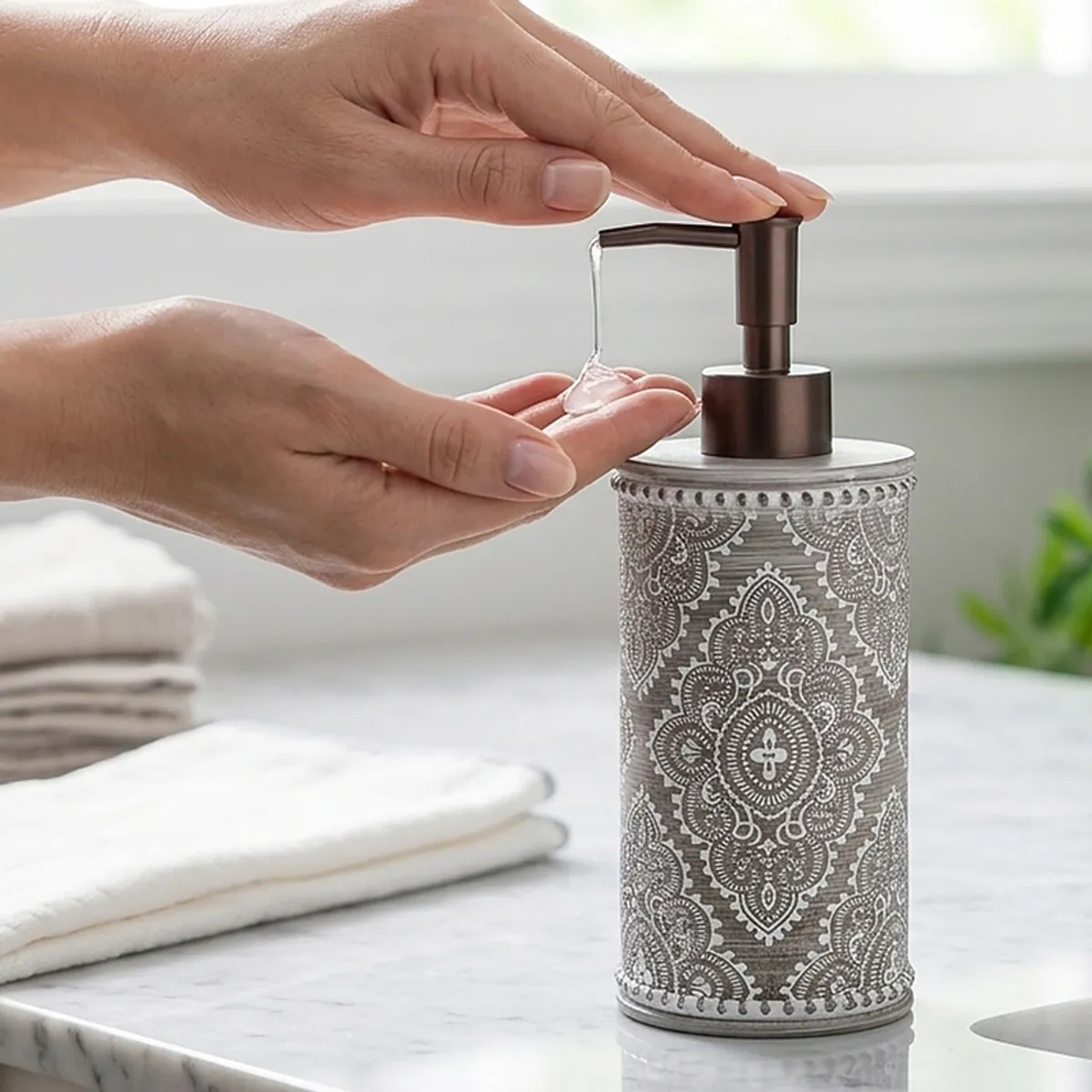 Hand pressing pump on grey patterned liquid soap dispenser