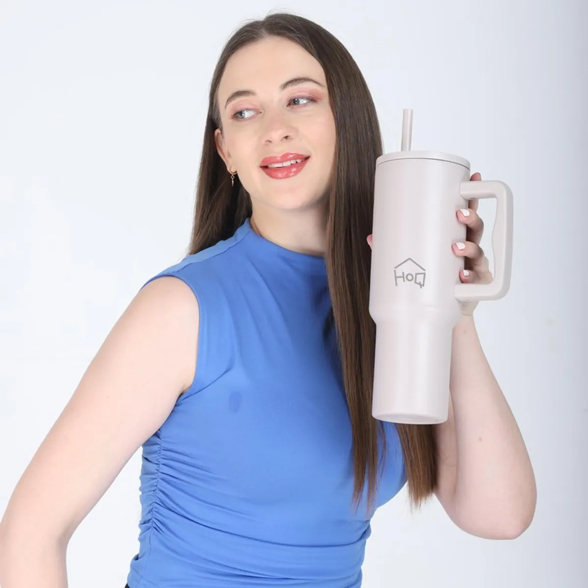 Woman holding a tall oat beige tumbler with handle and straw