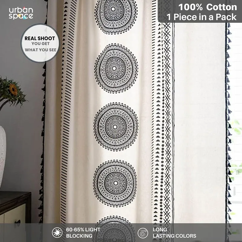 Close view of black and white curtain with repeated circular motifs and tasseled trim