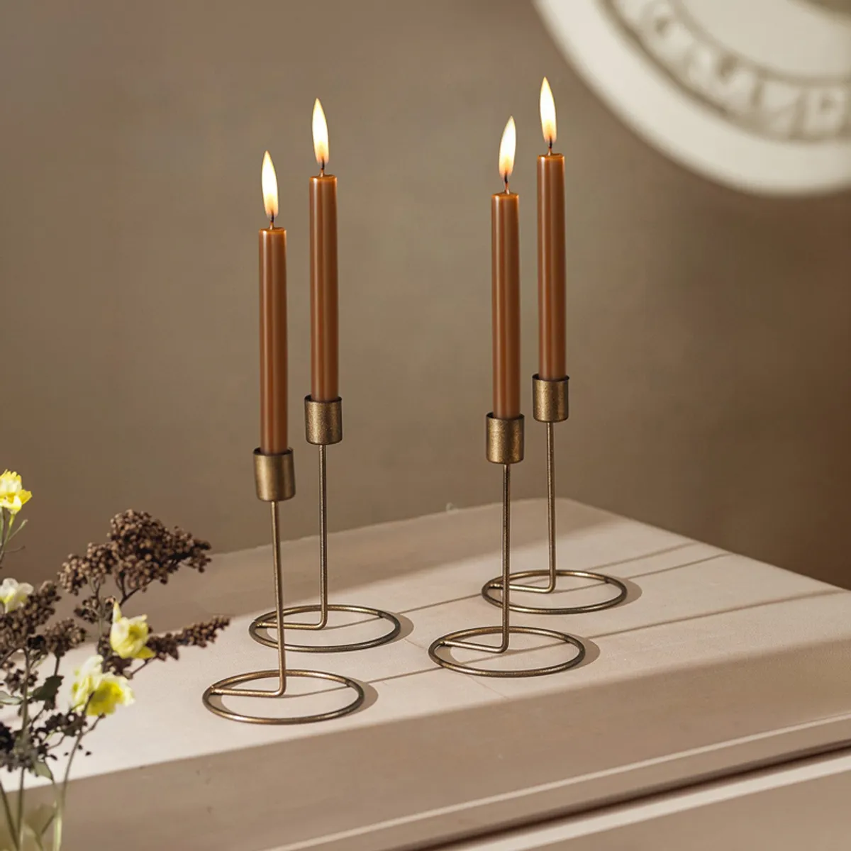 Four brown tealight holders arranged on a tabletop with lit candles