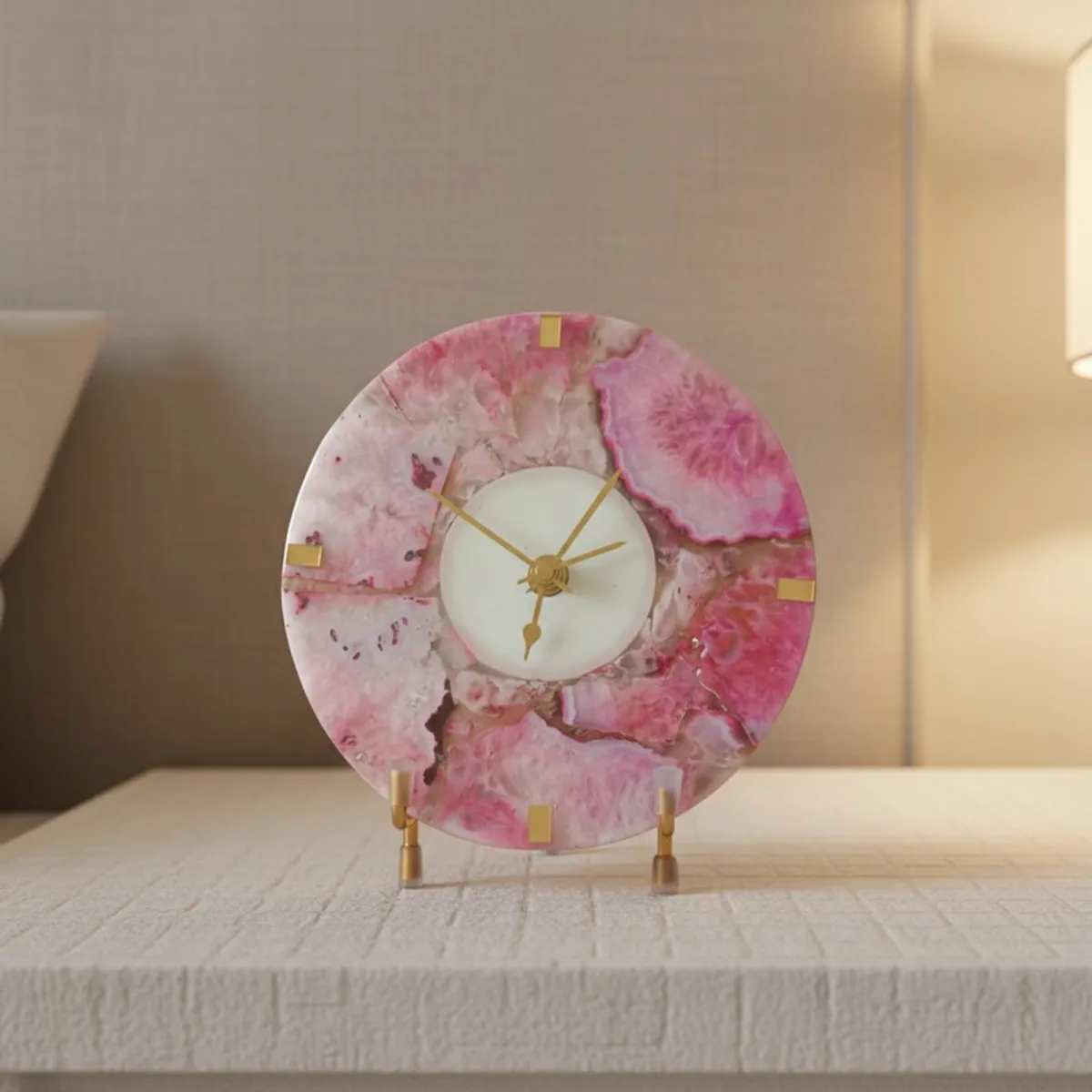 Rose agate round table clock with gold details displayed on a textured shelf
