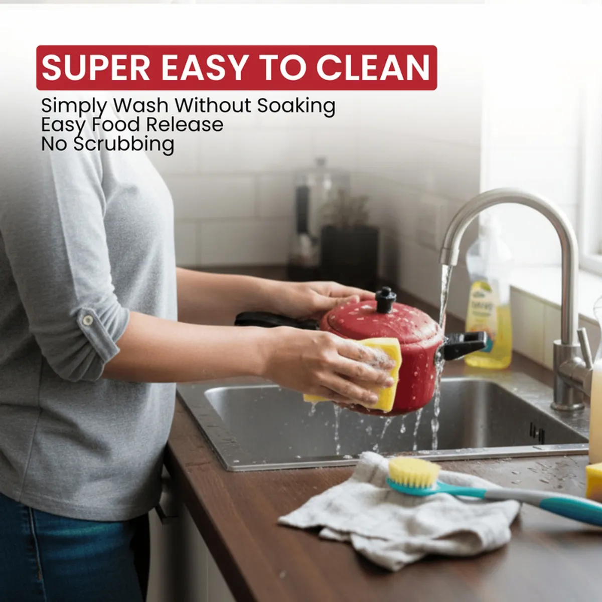 Person washing a red lidded cookware piece at a kitchen sink