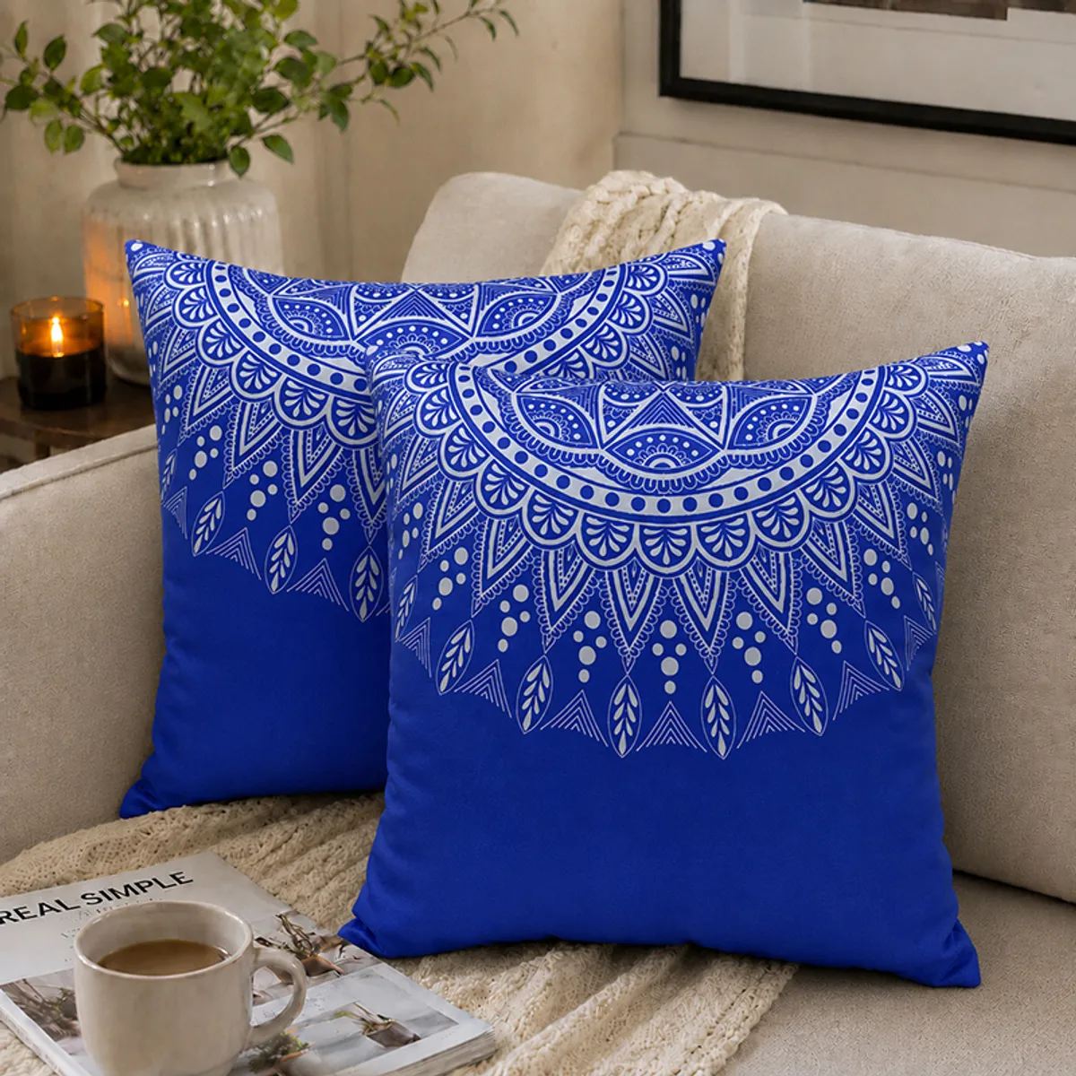 Two blue square cushion covers with white mandala prints styled on a sofa