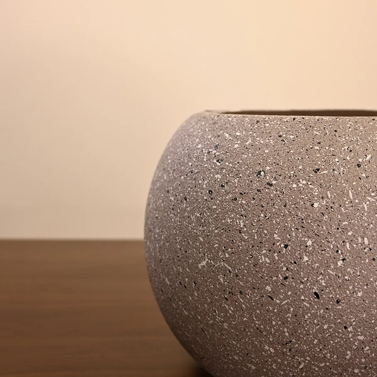 Close-up view of the speckled textured surface and rim of a grey planter