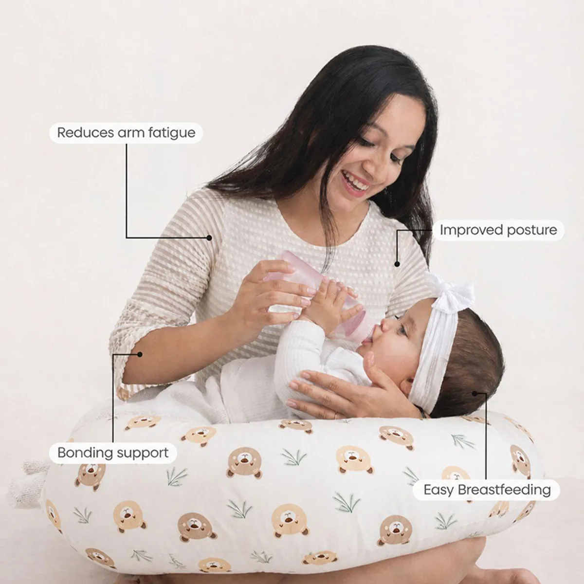 Baby lying on a white bear-print feeding pillow while being bottle-fed