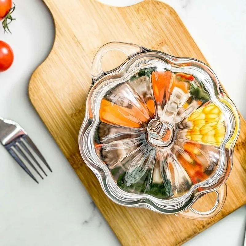 Top view of transparent glass bowl with sculpted lid and colourful food on a wooden board