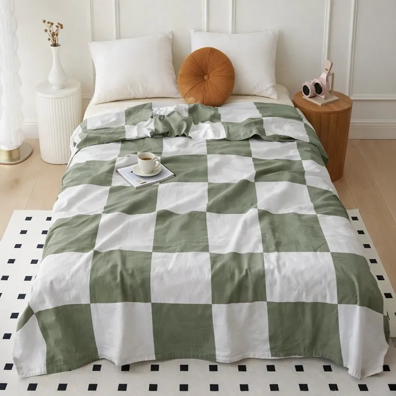 Green and white checked dohar styled on a bed with white pillows