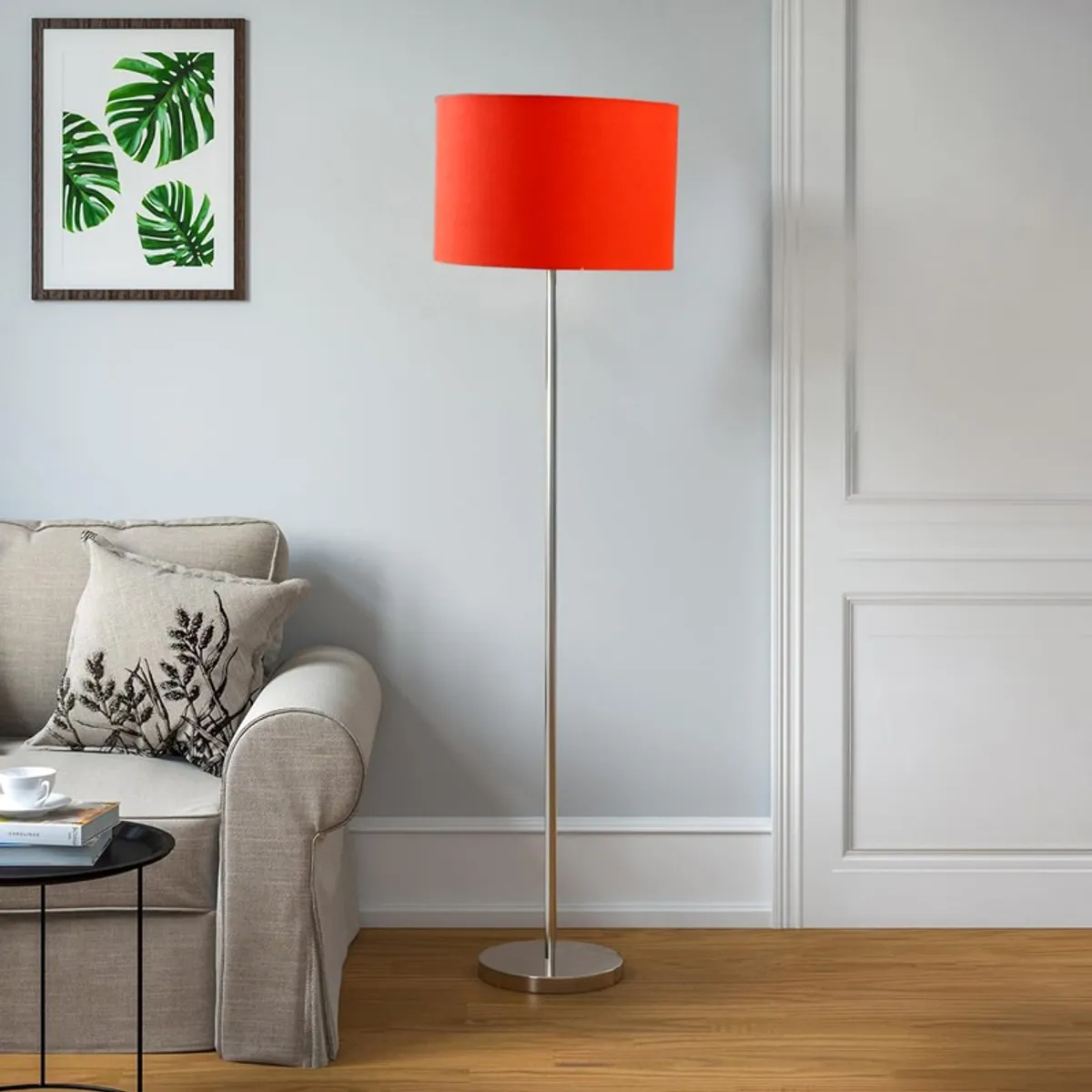 Orange floor lamp with slim steel stand in a bright living room setting