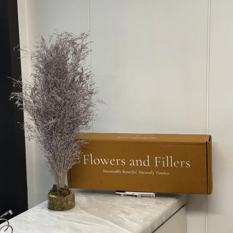 Purple dried grass arrangement displayed beside a decorative box