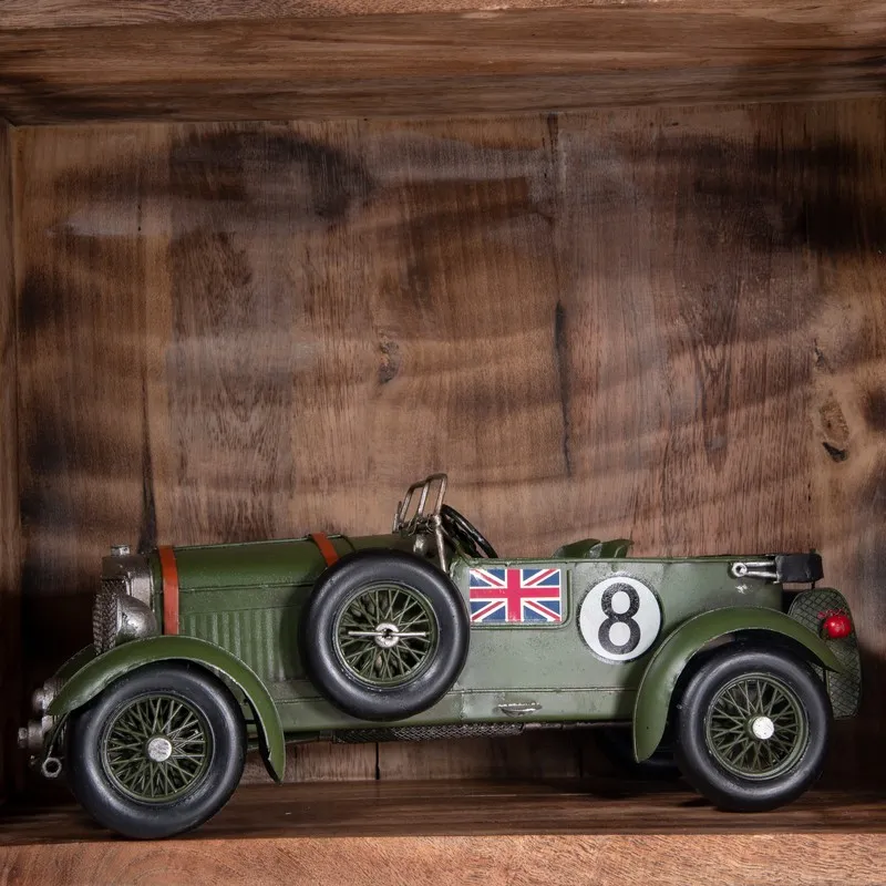 Side view of olive green British racer car showpiece on a wooden shelf