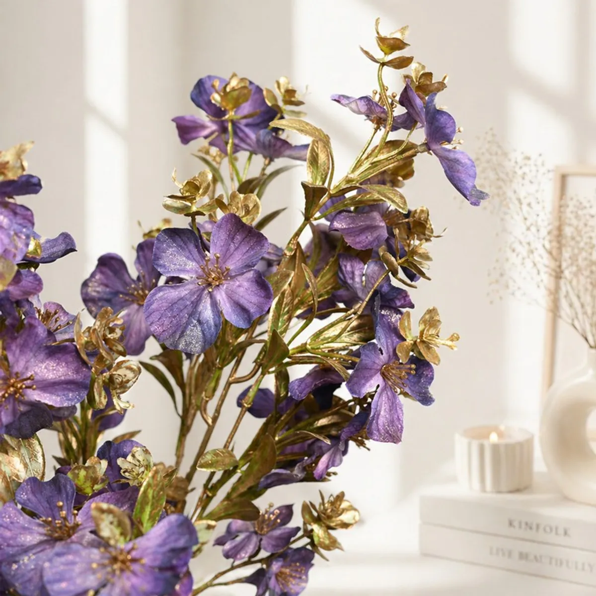 Close-up of purple blossoms with metallic gold foliage on artificial stems