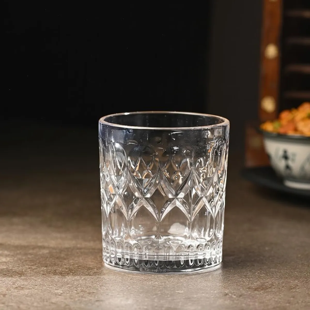 Single clear cut-pattern whiskey glass displayed on a dark table
