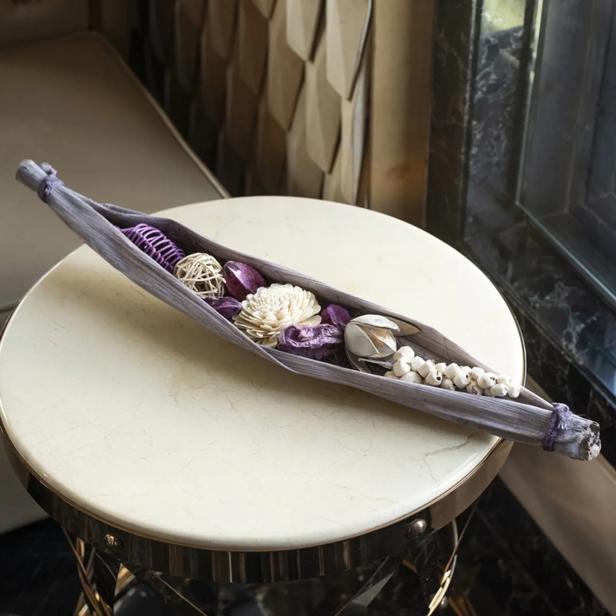 Purple and off-white artificial flower arrangement styled on a round tabletop.