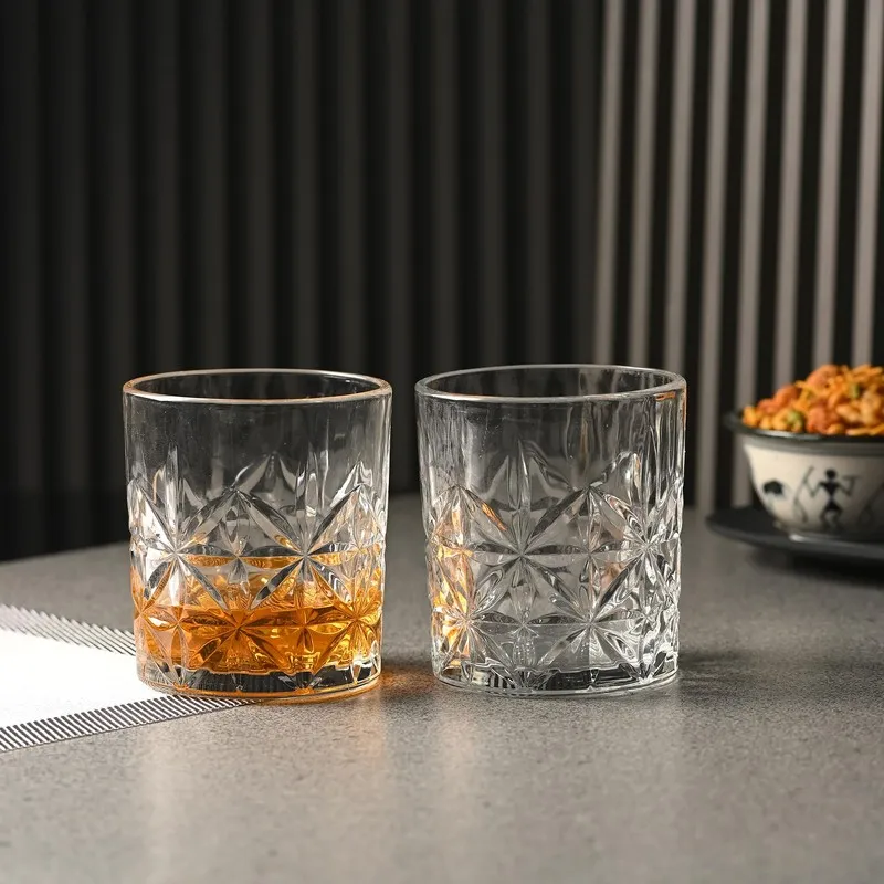 Two clear textured whiskey glasses on a tabletop