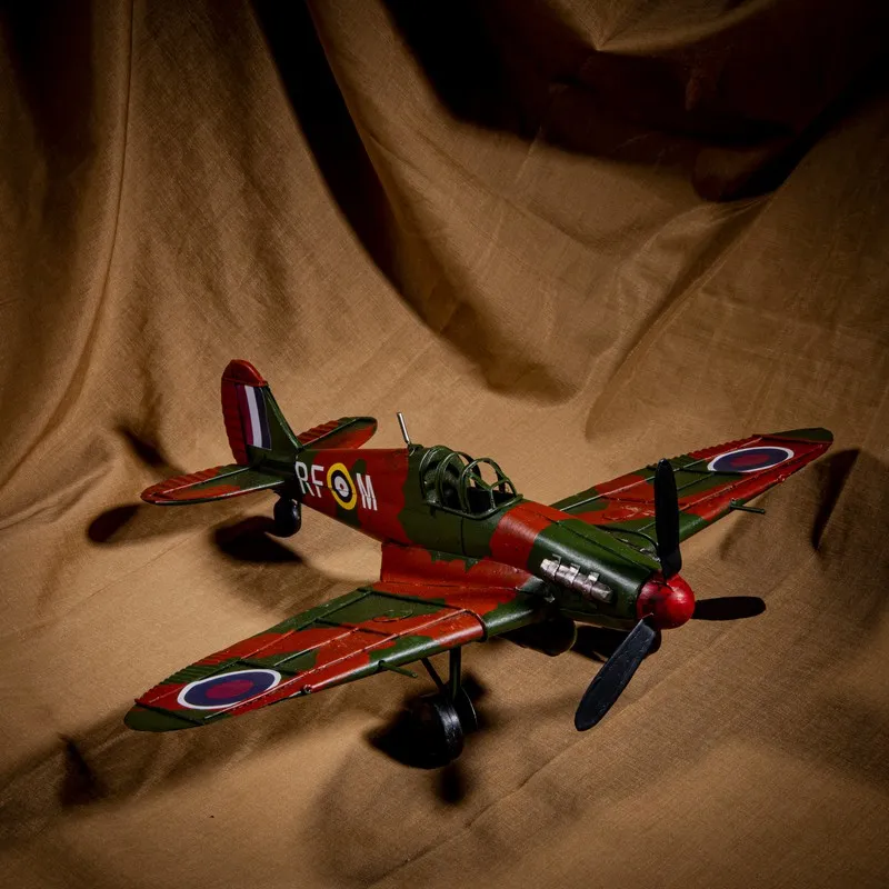 Red and green aeroplane showpiece with propeller and wheels against a draped backdrop