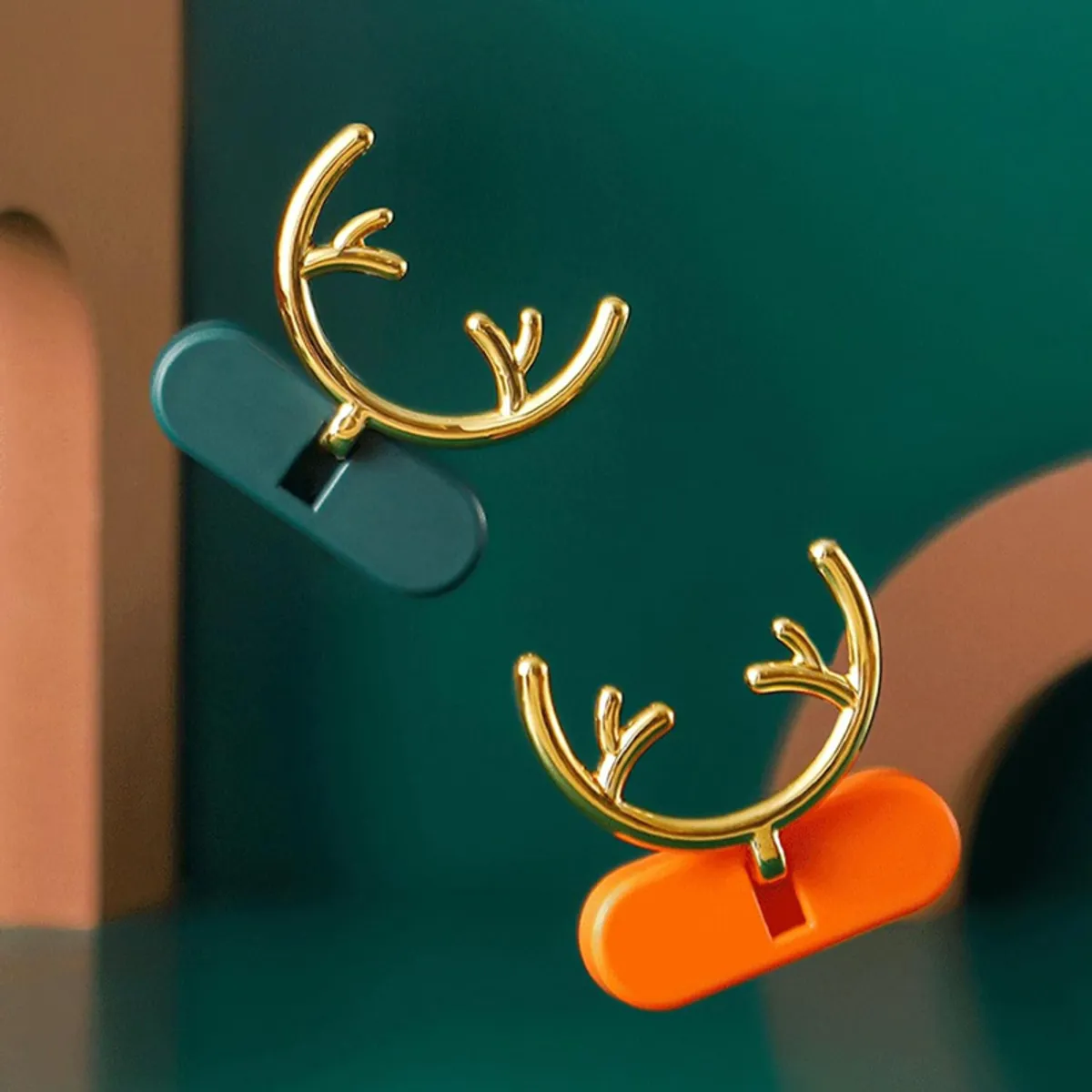 Close-up of two antler-shaped wall hooks in green and orange