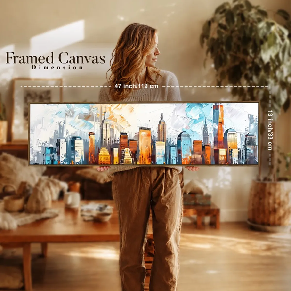 Person holding a wide framed cityscape canvas in a warm-toned living space.